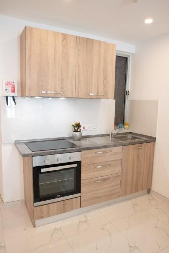 a kitchen with wooden cabinets and a stove top oven at For Rest Aparthotel in St Paul's Bay