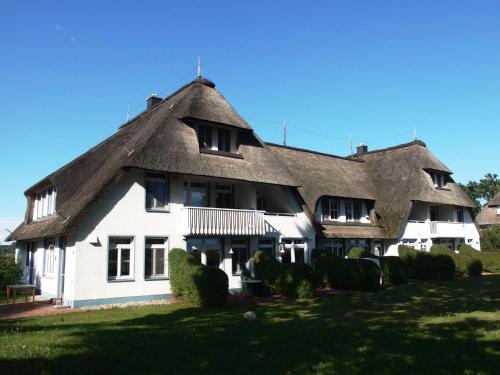 a large white house with a thatched roof at Landhaus am Haff_ Wohnung B 8 in Stolpe auf Usedom
