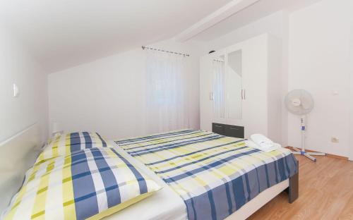 a white bedroom with two beds and a fan at modern in Duće
