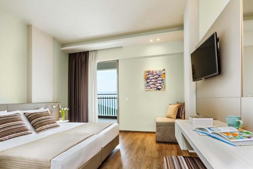 a hotel room with a bed and a tv at Ammon Zeus Luxury Beach Hotel in Kallithea Halkidikis