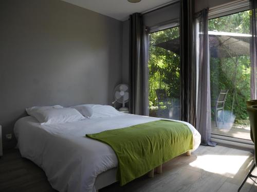 une chambre avec un lit avec une couverture verte dessus dans l'établissement Les Cabanes de Do, au Mans