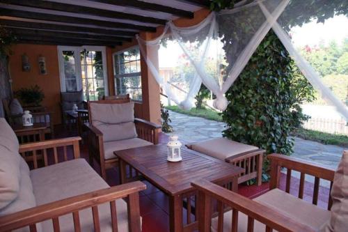 un patio al aire libre con mesas y sillas de madera y cenador en La Quintana del Cuera, en Parres de Llanes