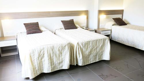 a hotel room with two beds with white sheets at Hôtel La Source in Lourdes