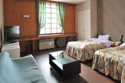 a hotel room with two beds and a tv at Mogamitakayu Zenshichinoyu Ohira in Zao Onsen