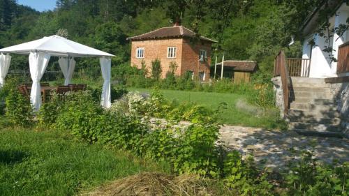 a garden with a white umbrella and a building at Smart and Cozy Nature House in Belogradchik