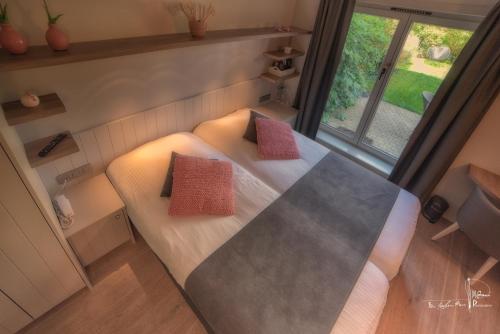 a small room with a bed with red pillows on it at Hotel Bilderdijk in De Haan