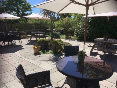a patio with a table and chairs and an umbrella at Lastra Farm Hotel in Amlwch