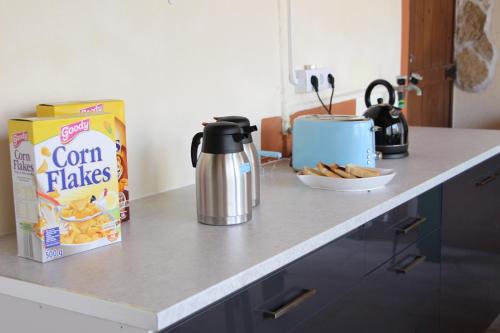 a counter top with a box of corn flakes cereal and a kettle at Casa o Futuro in Alcobaça