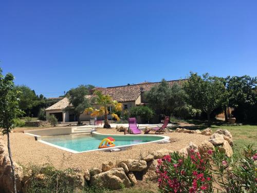 a swimming pool in a yard with chairs and a house at Mas de la Frigoule in Le Pouget