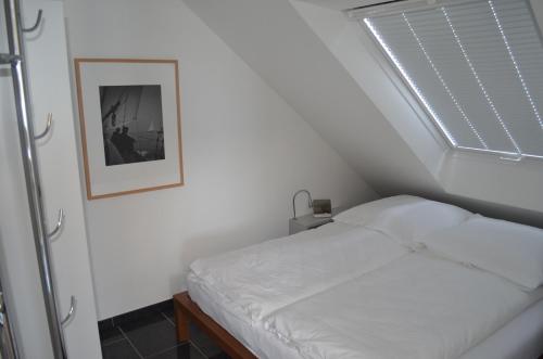 ein weißes Bett in einem Zimmer mit Fenster in der Unterkunft Dünenblick Apartments in Helgoland