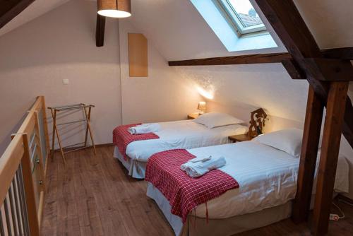 2 bedden in een zolderkamer met een raam bij Au gre des chateaux in Goxwiller