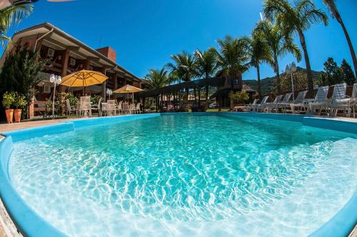 a swimming pool at a resort with chairs and palm trees at Pousada Ponta do Lobo in Balneário Camboriú