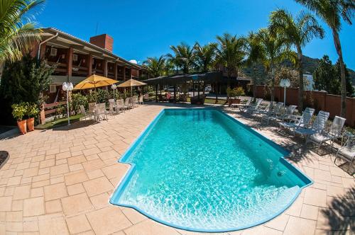 a large swimming pool with chairs and a building at Pousada Ponta do Lobo in Balneário Camboriú