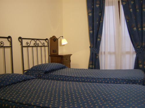 two twin beds in a bedroom with blue curtains at La Locanda di Castromediano - Al Becco della Civetta in Castelmezzano