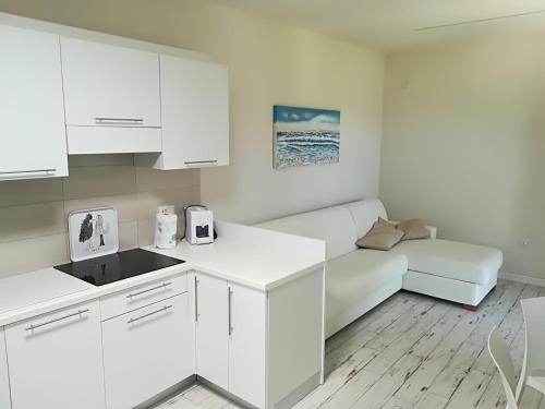 a kitchen with white cabinets and a couch at Giardino Don Berardino in Mattinata