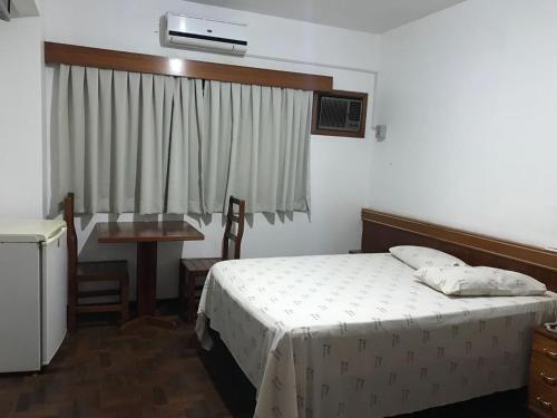 een slaapkamer met een bed, een tafel en een raam bij Hotel Firenze in Londrina