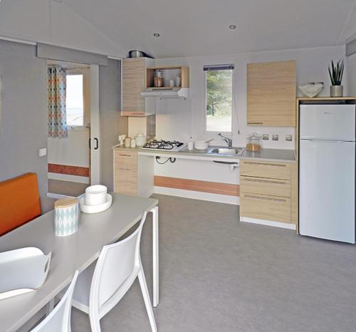 a kitchen with a table and a white refrigerator at Camping Harfenmühle - Mobilheim in Mörschied