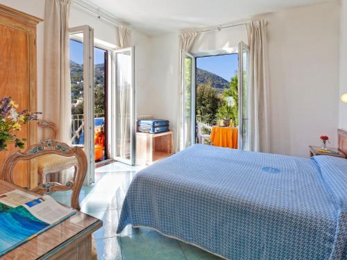 a bedroom with a blue bed and a balcony at Hotel Cleopatra in Ischia