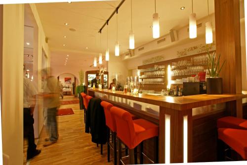 a bar in a restaurant with orange chairs at Hotel Restaurant Pusswald in Hartberg