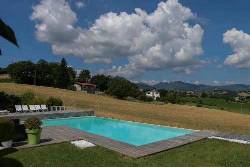 a swimming pool in the middle of a yard with a field at Serre Alte Landscape Luxury Rooms in Matelica