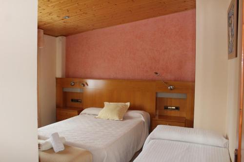Un pequeño dormitorio con 2 camas y un banco en Apartamentos Turísticos Can Rocamora en Aren