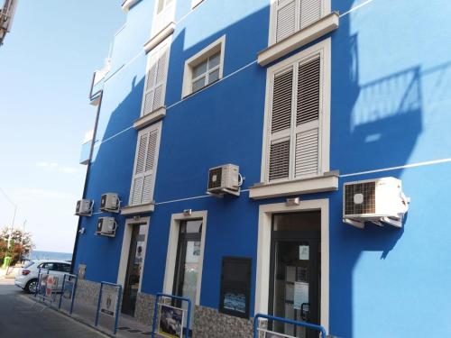 a blue building with windows and a car parked in front at Affacciati sulle Eolie Appartamenti sul Lungomare Patti Marina in Patti