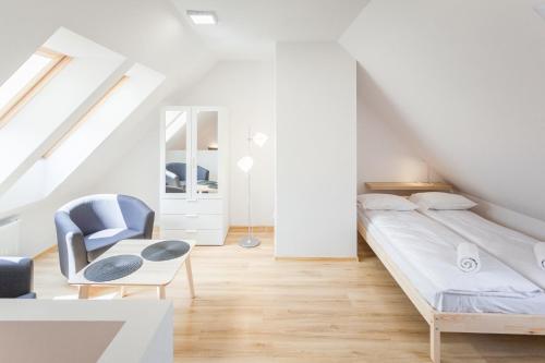 a white bedroom with a bed and a chair at Sudety Park MyWeek in Polanica-Zdrój