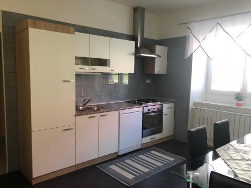 a kitchen with white cabinets and a sink at Apartma Mahnič in Postojna