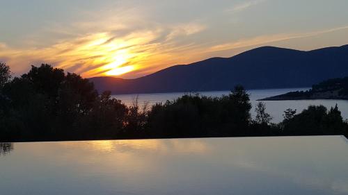 a sunset over a body of water with mountains at Villa Del Mar in Vasiliki