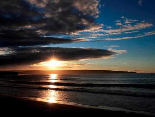 a sunset on the beach with the sun setting at Norseman Hotel in Wick