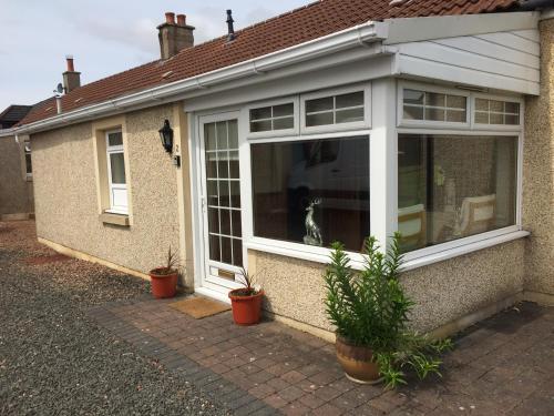 a dog sitting in a window of a house at Pippin, Tranquil Scottish Cottage with Hot Tub in Airdrie