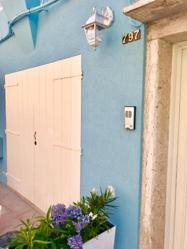 a blue wall with a white door and flowers at Barbara’s rooms in Chioggia