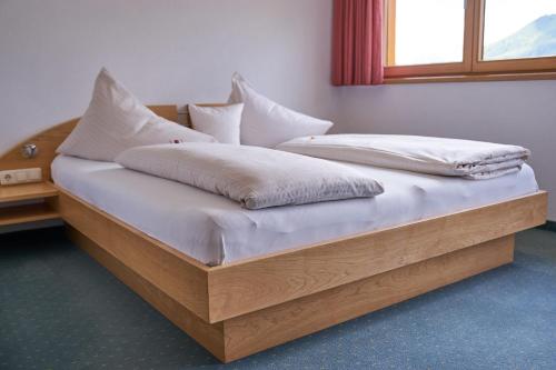 a wooden bed with white sheets and pillows on it at dr'Berghof in Damuls