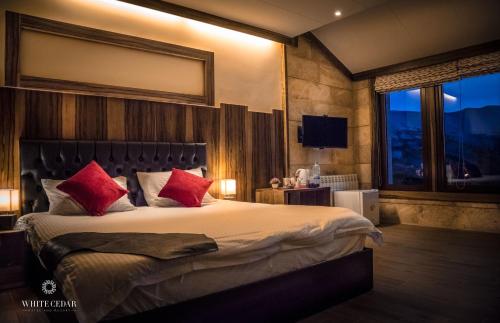una camera da letto con un grande letto con cuscini rossi di White Cedar Hotel &Resort a Al Arz