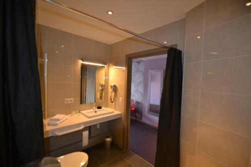 a bathroom with a sink and a toilet and a mirror at Hôtel Restaurant Les Alizés in Lipsheim