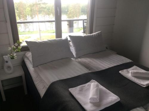 uma cama com toalhas num quarto com uma janela em Naava Chalet 304 Pandatupa em Ahtari