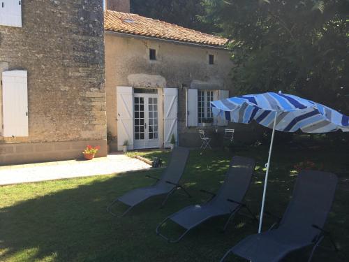 a group of chairs and an umbrella in a yard at Le Logis de Limalonges in Limalonges