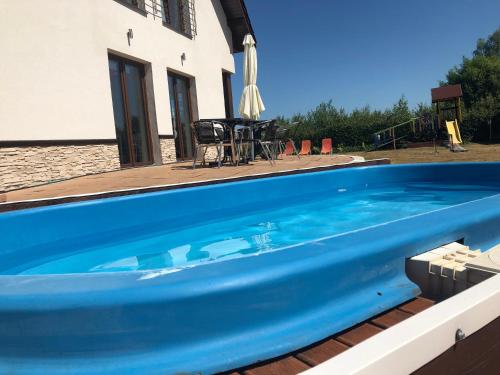 a large blue swimming pool next to a house at Apartamenty i Pokoje Na Letniej in Darłowo