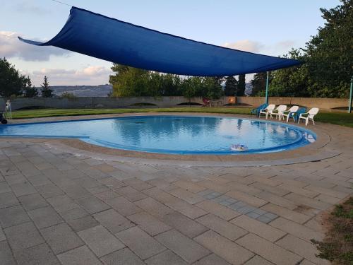 a swimming pool with a blue canopy over it at הים פוגש את ההר- בית בלב הגליל Sea & Mount in Adamit