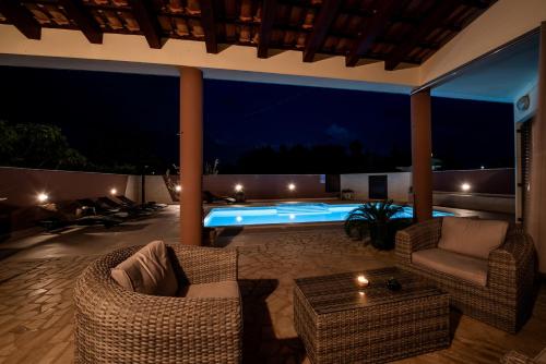 a patio with chairs and a swimming pool at night at Villa Komel with Pool in Fažana
