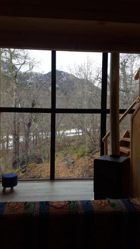 a large window in a bedroom with a view of a mountain at Andrómeda Lodge in Las Trancas