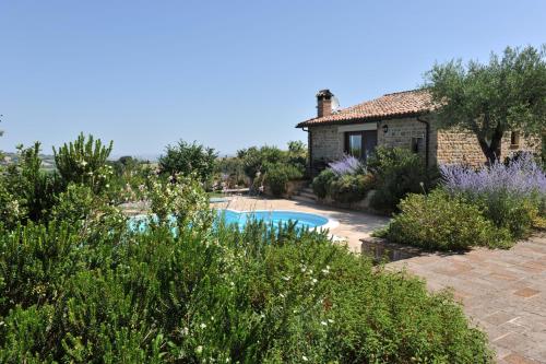 a house with a swimming pool in a garden at Il Picchio Verde in SantʼAngelo in Pontano