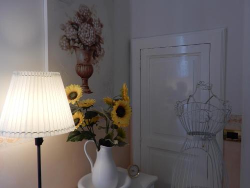 a vase of sunflowers in a room with a lamp and a v at Luciano And Son in Campobasso