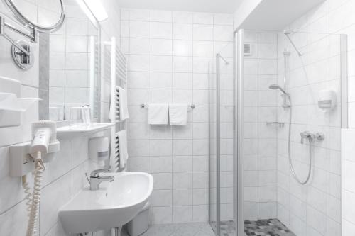 a white bathroom with a sink and a shower at Landhotel Häuserl im Wald in Gröbming