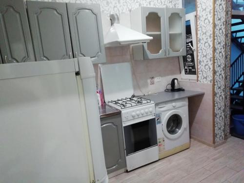 a kitchen with a refrigerator and a washing machine at Nikos Guest House in Adler