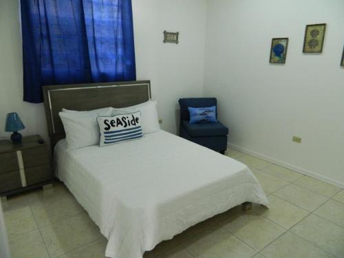 a bedroom with a bed with a pillow and a chair at Blue House Joyuda in Cabo Rojo
