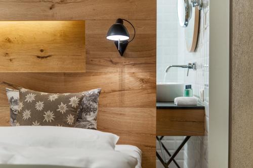 a bedroom with a bed and a sink and a lamp at Aqua Dome 4 Sterne Superior Hotel & Tirol Therme Längenfeld in Längenfeld