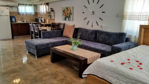 a living room with a couch and a table and a clock at Tiberias Vacation Rental in Tiberias