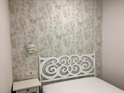 1 dormitorio con cama blanca y papel pintado en APARTAMENTO SAN MIGUEL N.2, en Jarandilla de la Vera