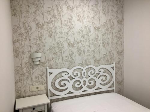 ハランディージャ・デ・ラ・ベラにあるAPARTAMENTO SAN MIGUEL N.2の白いベッドと壁紙が備わるベッドルーム1室が備わります。